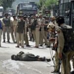 Indian security personnel stand next to the body of a suspected militant after an attack at the Jammu-Srinagar national highway near Udhampur